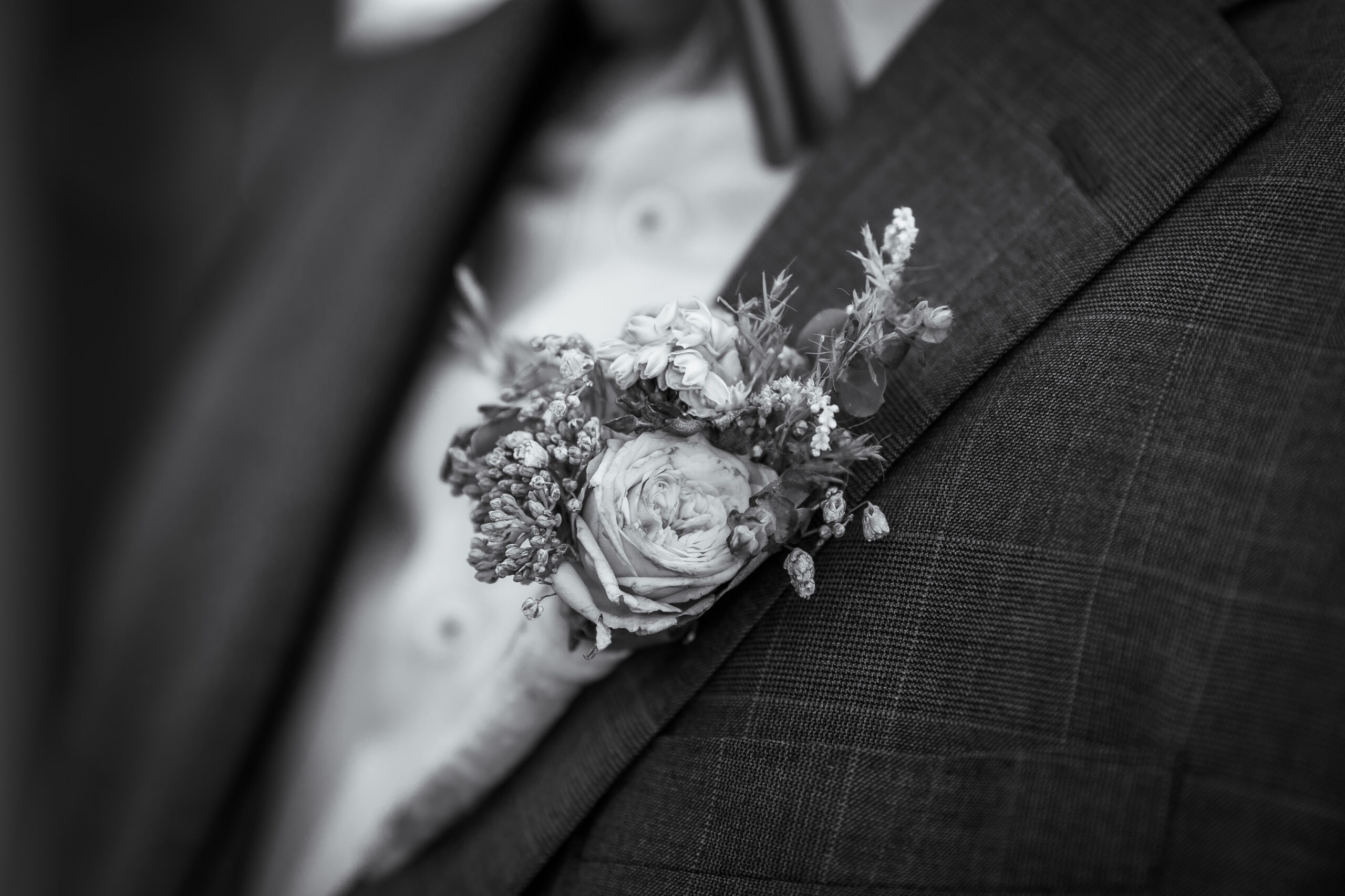 Der Blumenschmuck an einem Sakko eines Bräutigams. Ein Foto in schwarz weiß. Hochzeitsfotograf aus Neuss - Bresser-Photography