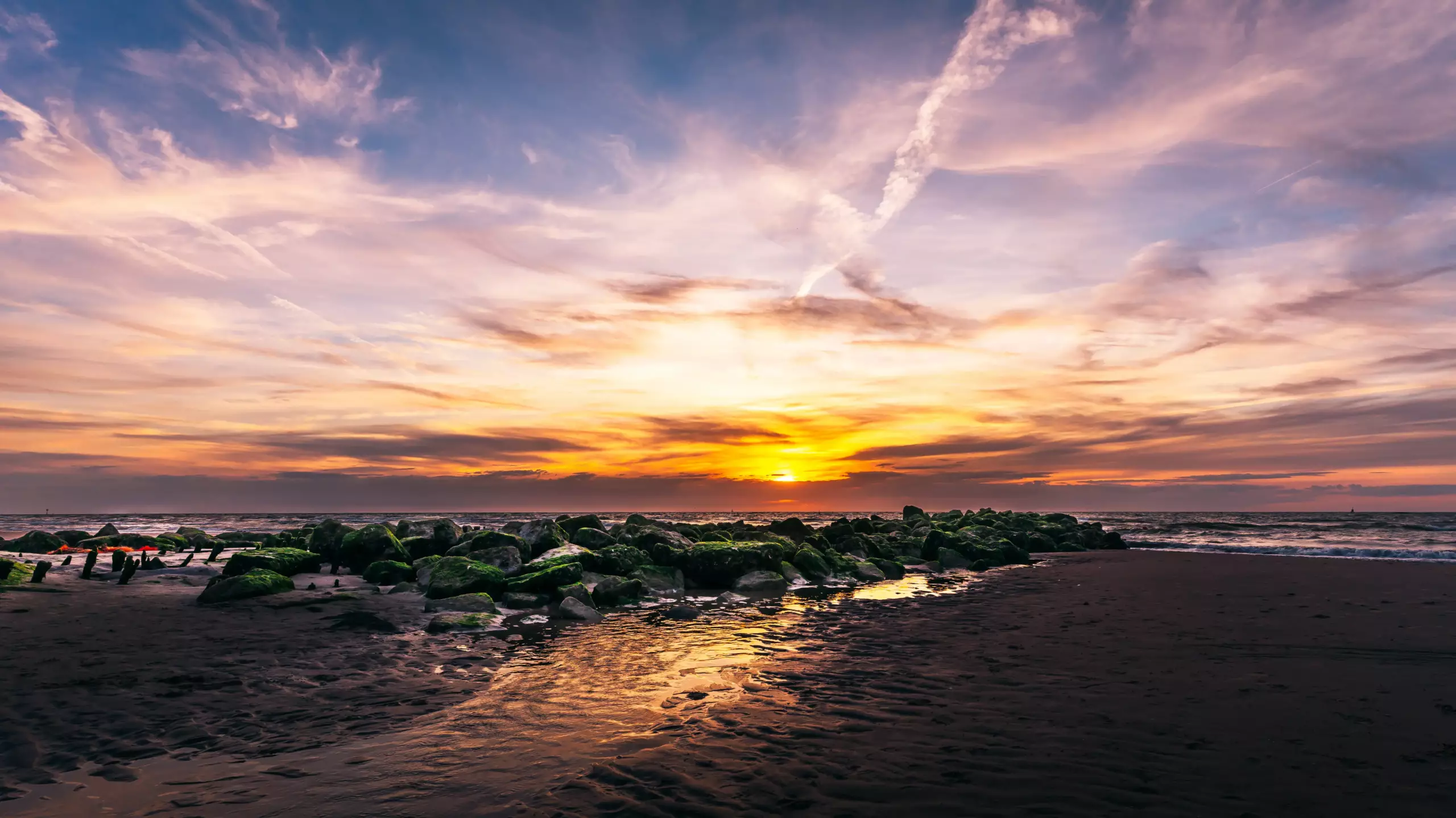 Der Sonnenuntergang an einem Strand in den Niederlanden. Im Vordergrund befinden sich Steine welche sich am Strand befinden Landschaftsfoto - Bresser-Photography