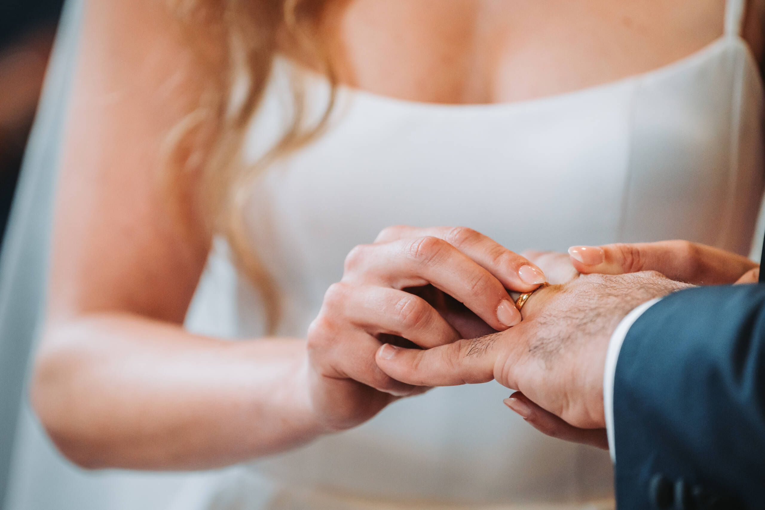 Die Braut steckt den Ehering auf den Ringfinger des Bräutigams während der Zeremonie einer kirchlichen Trauung.